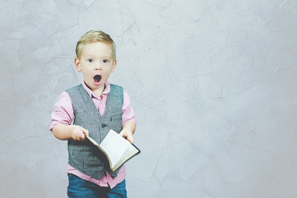 young boy with surprised face holding bible with textured background